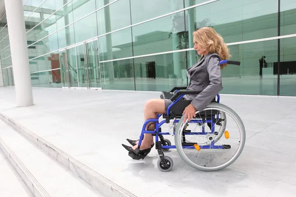 Женщина в инвалидной коляске возле офисного здания — стоковое фото
