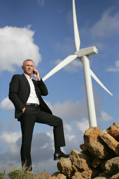 Homem ao telefone em frente ao moinho de vento — Fotografia de Stock