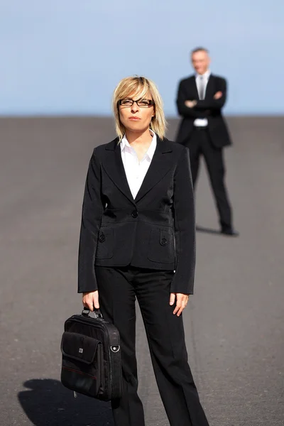 彼女の同僚から遠く離れて立っている金髪の女性実業家 — Stock fotografie