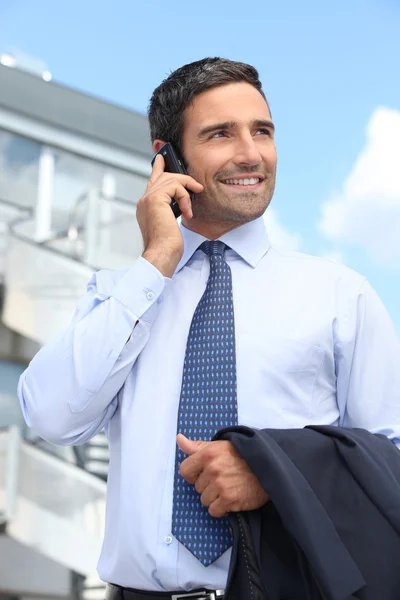 Empresário falando em um celular fora de um prédio de escritórios — Fotografia de Stock