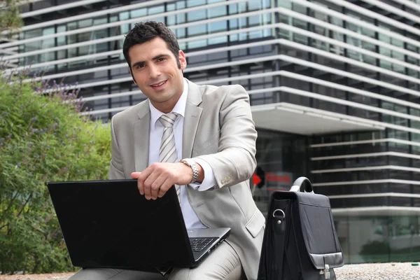 Hombre joven usando el ordenador portátil al aire libre — Foto de Stock