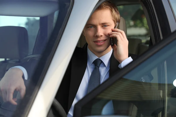 Juniorchef am Telefon am Steuer eines Luxusautos — Stockfoto