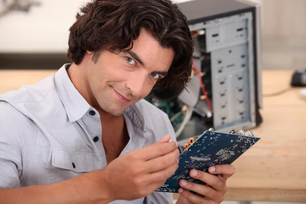 Человек с длинными волосами чинит компьютер. — стоковое фото