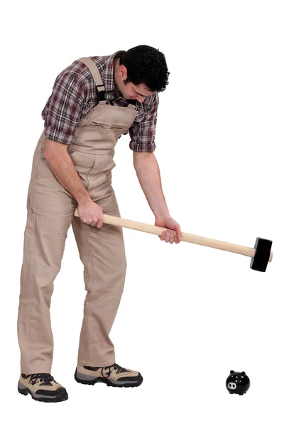 Hombre rompiendo alcancía con martillo de trineo — Foto de Stock