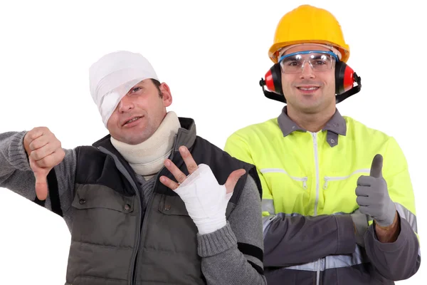 stock image Healthy construction worker standing next to an injured man