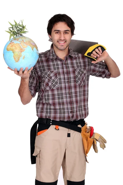 Tradesman holding a globe and saw — Stock Photo, Image