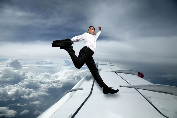 Homem de terno pulando na asa de um avião — Fotografia de Stock