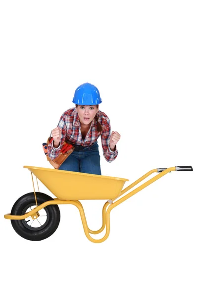 Woman with expression of relief crouching in a wheelbarrow — Stock Photo, Image