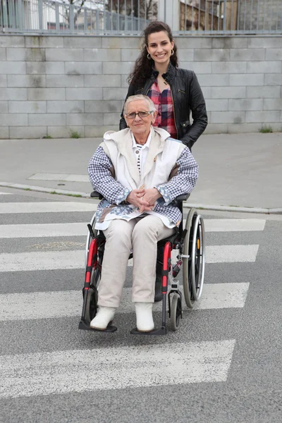 Dívka tlačí starší žena na vozíku — Stock fotografie