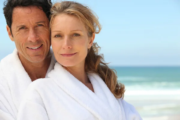 Pareja en albornoces en la playa — Foto de Stock