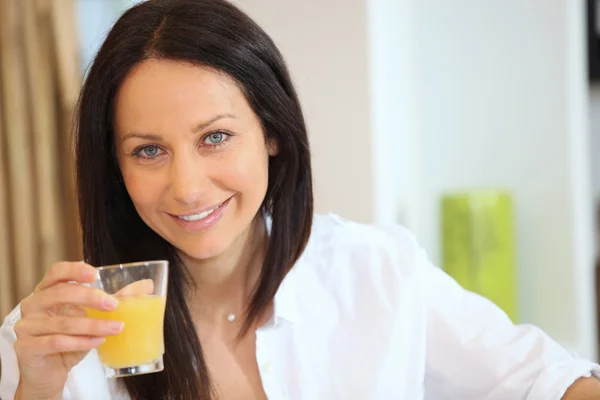 Beautiful brunette drinking orange juice — Stock Photo, Image