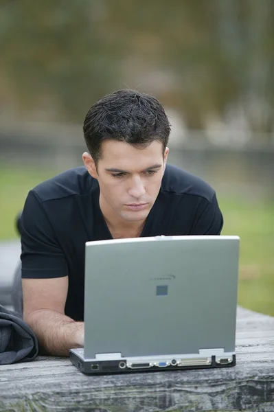 Человек, работающий в парке благодаря ноутбуку — стоковое фото