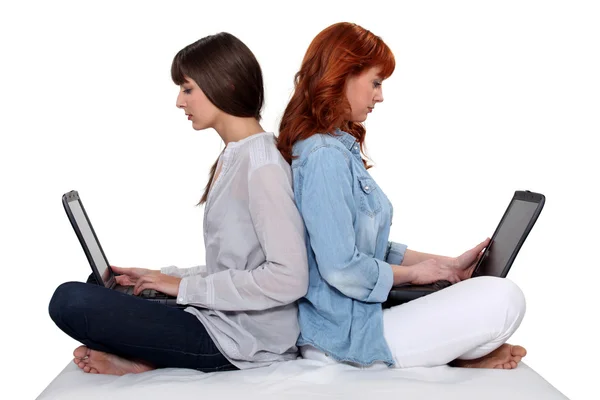 Dos amigas se sentaron espalda con espalda con ordenadores portátiles —  Fotos de Stock