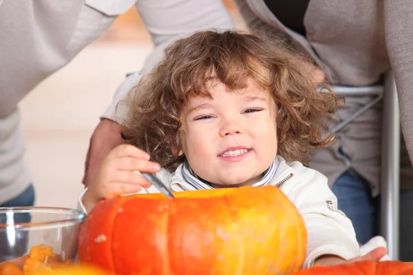 A plump kid carving a pumpkin. — Stock Photo, Image