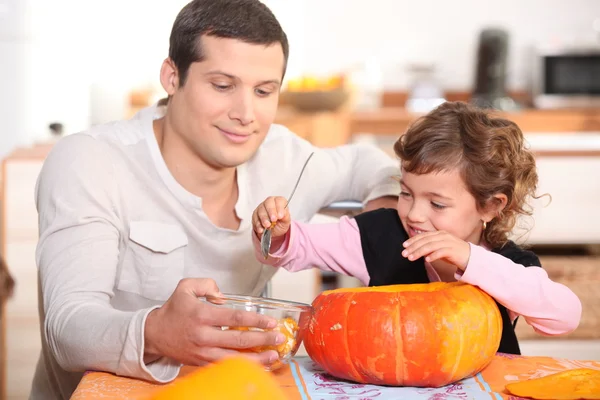 Dad and daughter hollowing out a pumpkin — Stock Photo, Image