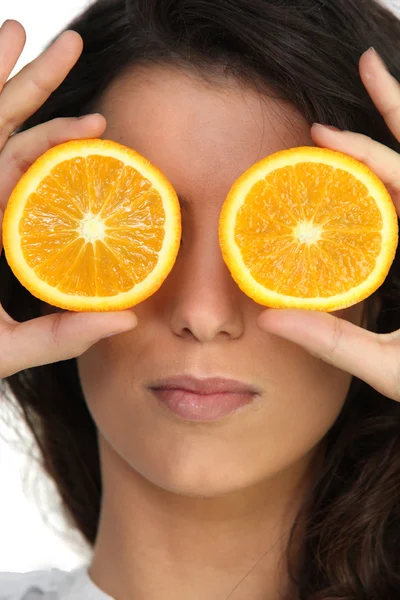 Hiding her eyes with oranges — Stock Photo, Image