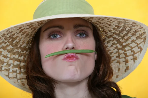 Frau balanciert grüne Bohne zwischen Lippen und Nase — Stockfoto