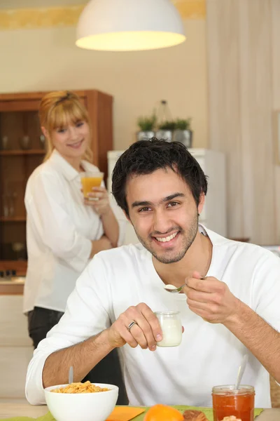 Happy man eating yoghurt for breakfast — Stock Photo, Image