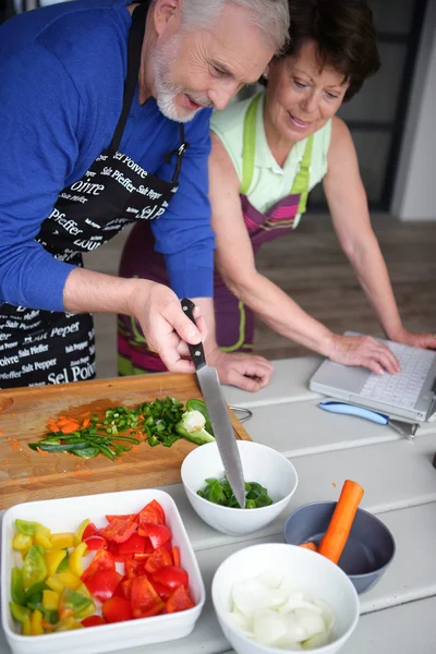 Senior koppel voorbereiding van een maaltijd op zoek naar een recept op internet — Stockfoto