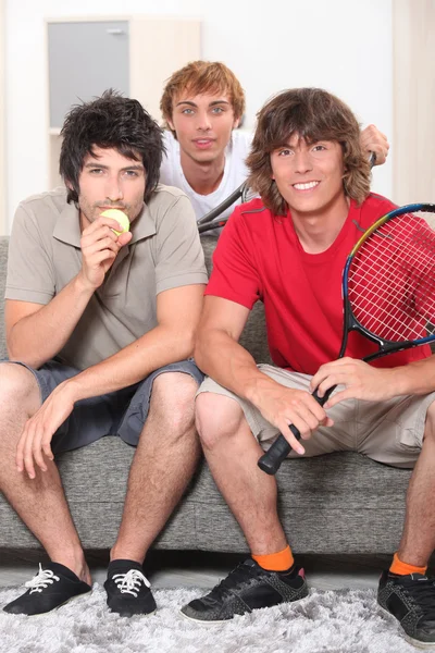 Facetów siedzi na kanapie z rakiety tenisowe — Zdjęcie stockowe