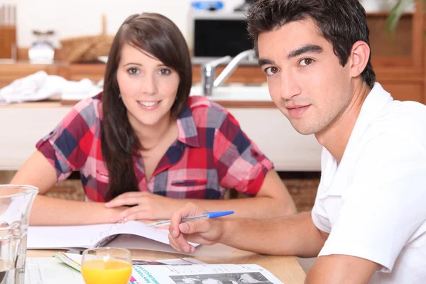 Giovane coppia che fa i compiti al tavolo della cucina — Foto Stock
