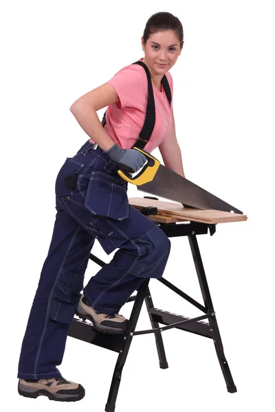 Woman sawing plank of wood Stock Picture