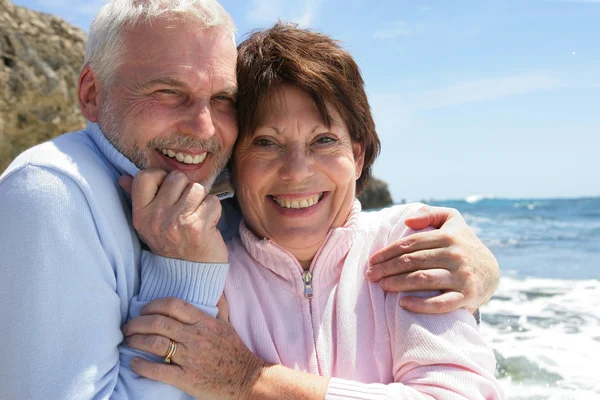 Ältere Paare umarmen sich am Meer lizenzfreie Stockbilder