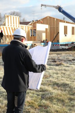 Construction site supervisor looking at a blueprint clipart