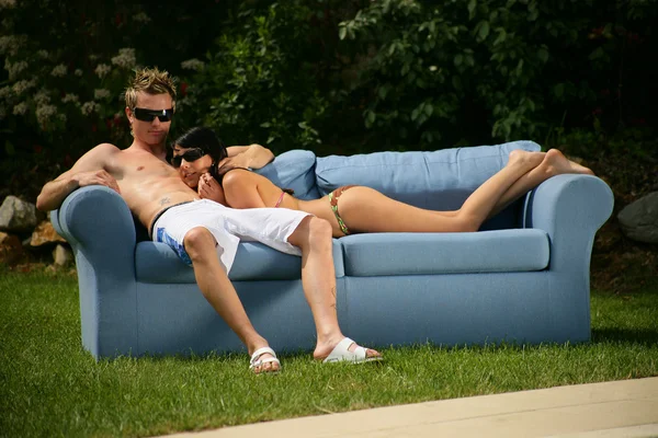 Couple wearing swim wear sat on sofa in the garden — Stock Photo, Image