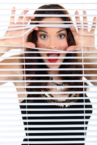 Vrouw gluren door blinds — Stockfoto