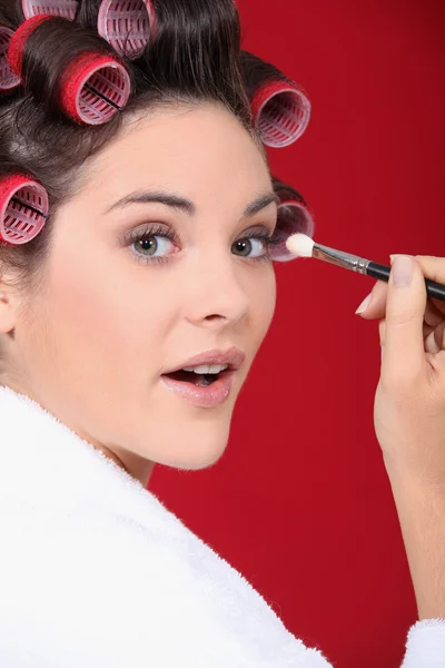 Woman with curlers in her hair putting make up — Stock Photo, Image