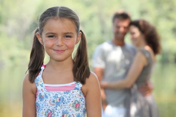 Une petite fille et ses parents dans un parc . — Photo