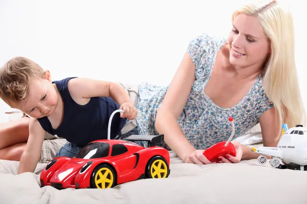 Тоддлер и мама играют с дистанционно управляемым спортивным автомобилем — стоковое фото