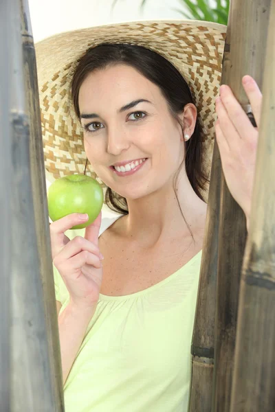 Жінка в капелюсі і тримає зелене яблуко — стокове фото