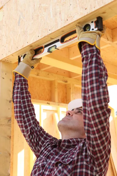 Pracownik budowlany za pomocą poziomnicy — Zdjęcie stockowe