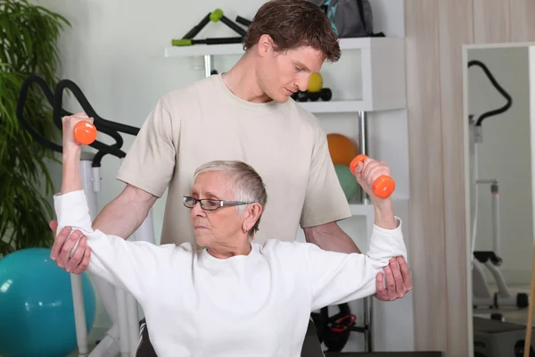 Senior woman working out with a personal trainer — Stok fotoğraf