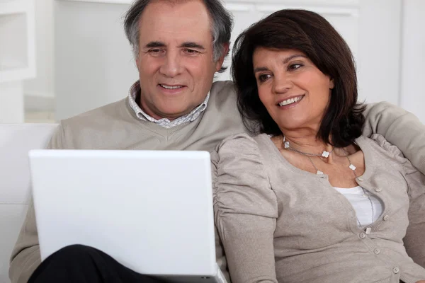 Pareja de mediana edad con portátil sentado en el sofá — Foto de Stock