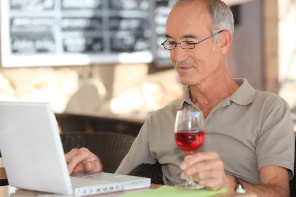 Senior man met zijn laptop in een café — Stockfoto