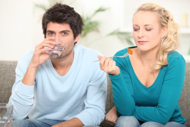 Couple eating a meal on the sofa clipart