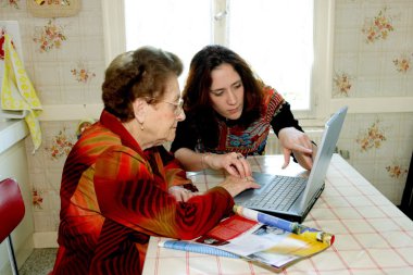 Woman helping grandmother with computer clipart