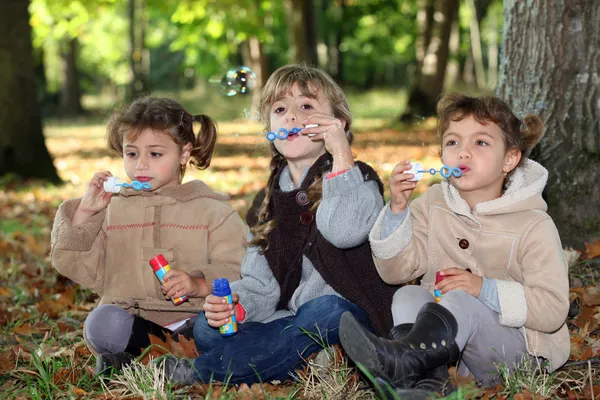 Young children blowing bubbles in the woods — Stock Photo, Image