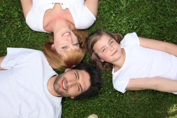 Familia vestida de blanco yaciendo en la hierba — Foto de Stock