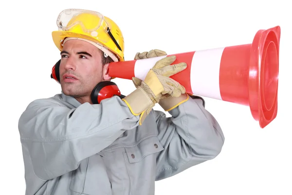 Manual worker holding traffic cone to ear — Stock Photo, Image