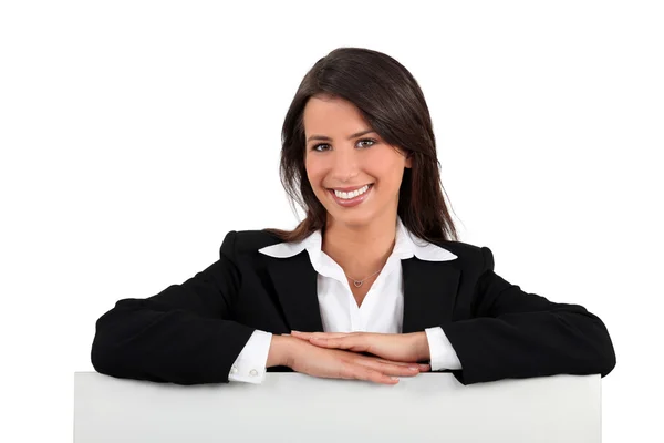 Businesswoman leaning on a board left blank for your message — Stock Photo, Image
