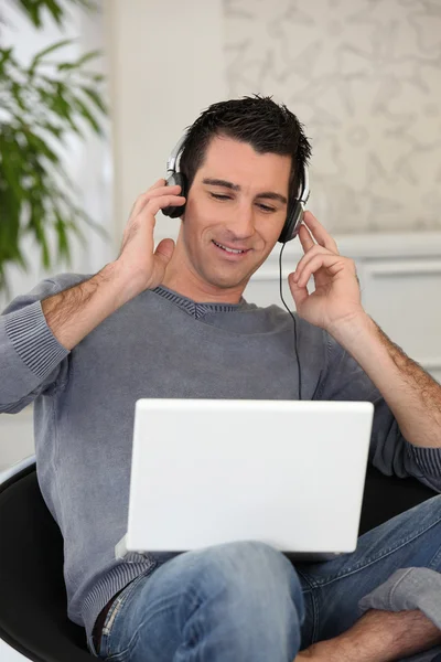 Člověk poslouchal jeho laptop na sluchátka — Stock fotografie