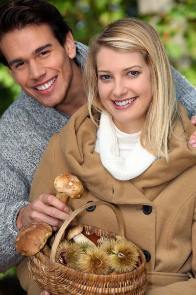 Young couple gathering mushrooms and chestnuts — Stock Photo, Image