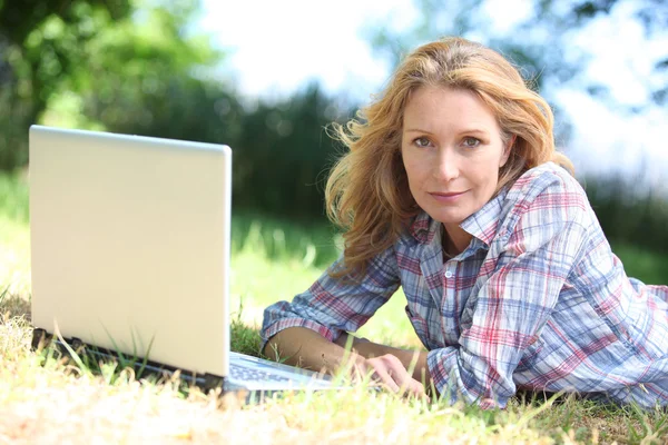 Kobieta, leżąc na trawie z laptopa — Zdjęcie stockowe