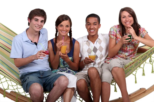 Un groupe d'amis dégustant des cocktails sur un hamac . — Photo