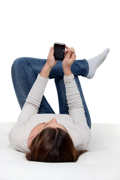 En kvinna som ligger och kontrollera sin telefon. — Stockfoto