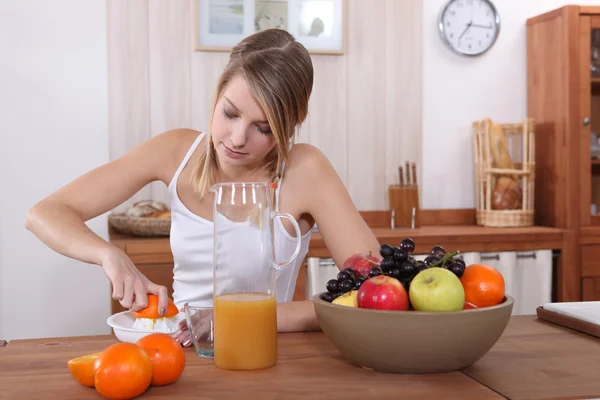 Linda rubia presionando naranja para el desayuno —  Fotos de Stock